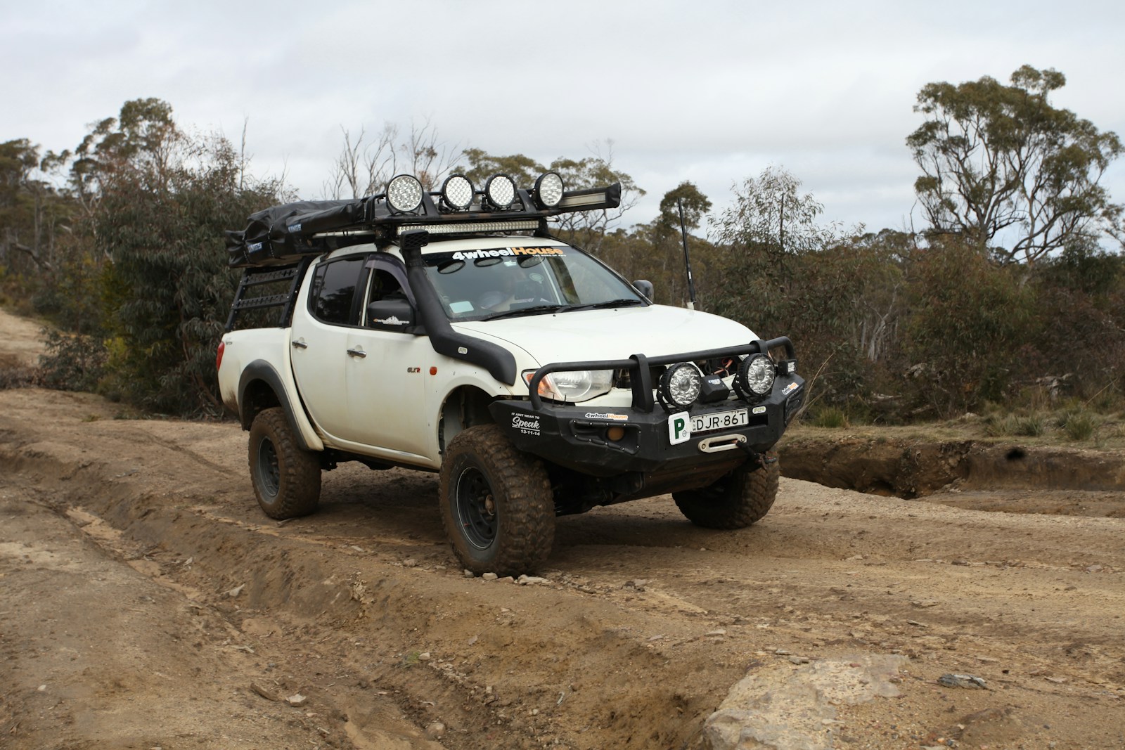 White off-road pickup truck driving on a dirt path